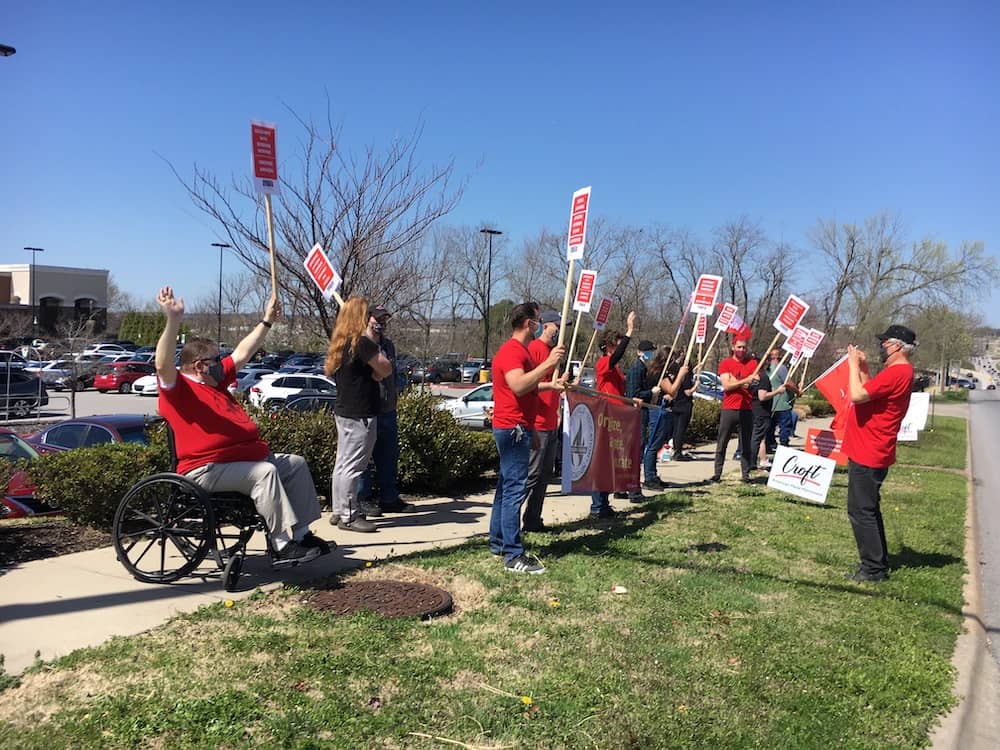 Red-shirted 965 members Hershel Hartford, Bret Schulte, Mike Pierce, Tricia Starks and Geoff Brock await Ted Swedenburg to shoot a photo at the Solidarity with Amazon Workers rally March 20, 2021, outside the Fayetteville Whole Foods Market.