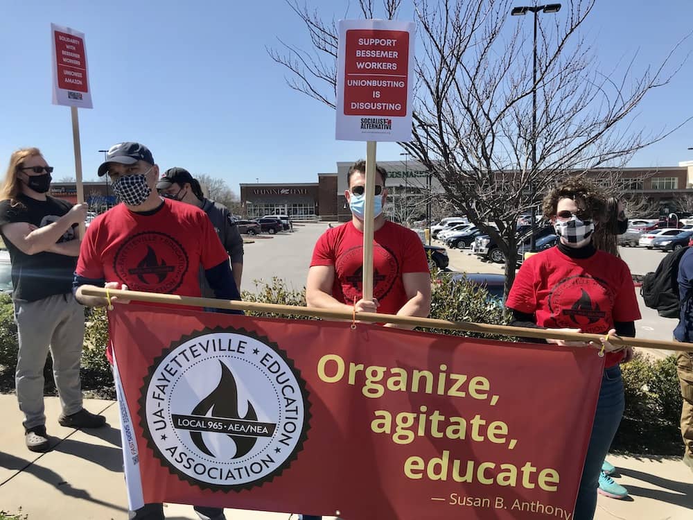 Mike Pierce, Bret Schulte and Tricia Starks hold the Local 965 banner at the Solidarity with Amazon Workers rally March 20, 2021, outside the Fayetteville Whole Foods Market.