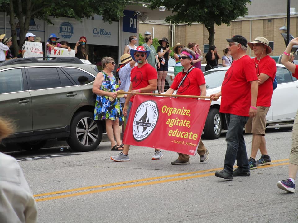 University of Arkansas workers Bret Schulte (from left), Ben Pollock, Ted Swedenburg and Mike Pierce represent Local 965 in the 17th annual Northwest Arkansas Pride Parade along Dickson Street in Fayetteville on June 26, 2021.