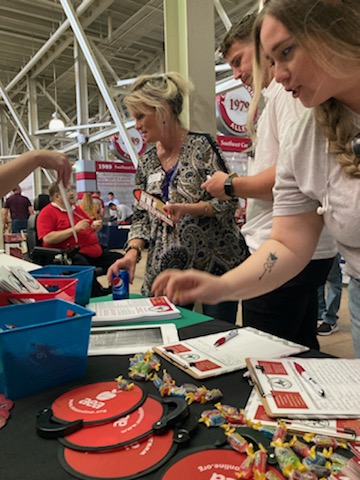 U of A staff members consider brochures and souvenirs at the Local 965 table May 19 at the 2022 Staff Appreciation Picnic at Reynolds Razorback Stadium.