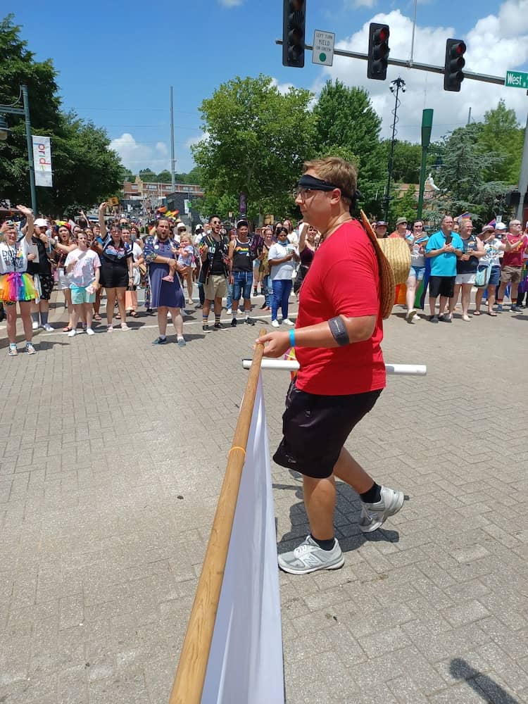 A friend of the union holds up one end of the banner of UA-Fayetteville Education Association/Local 965 heading down Dickson Street in the 2nd annual Fayetteville Trans March June 18, 2020.