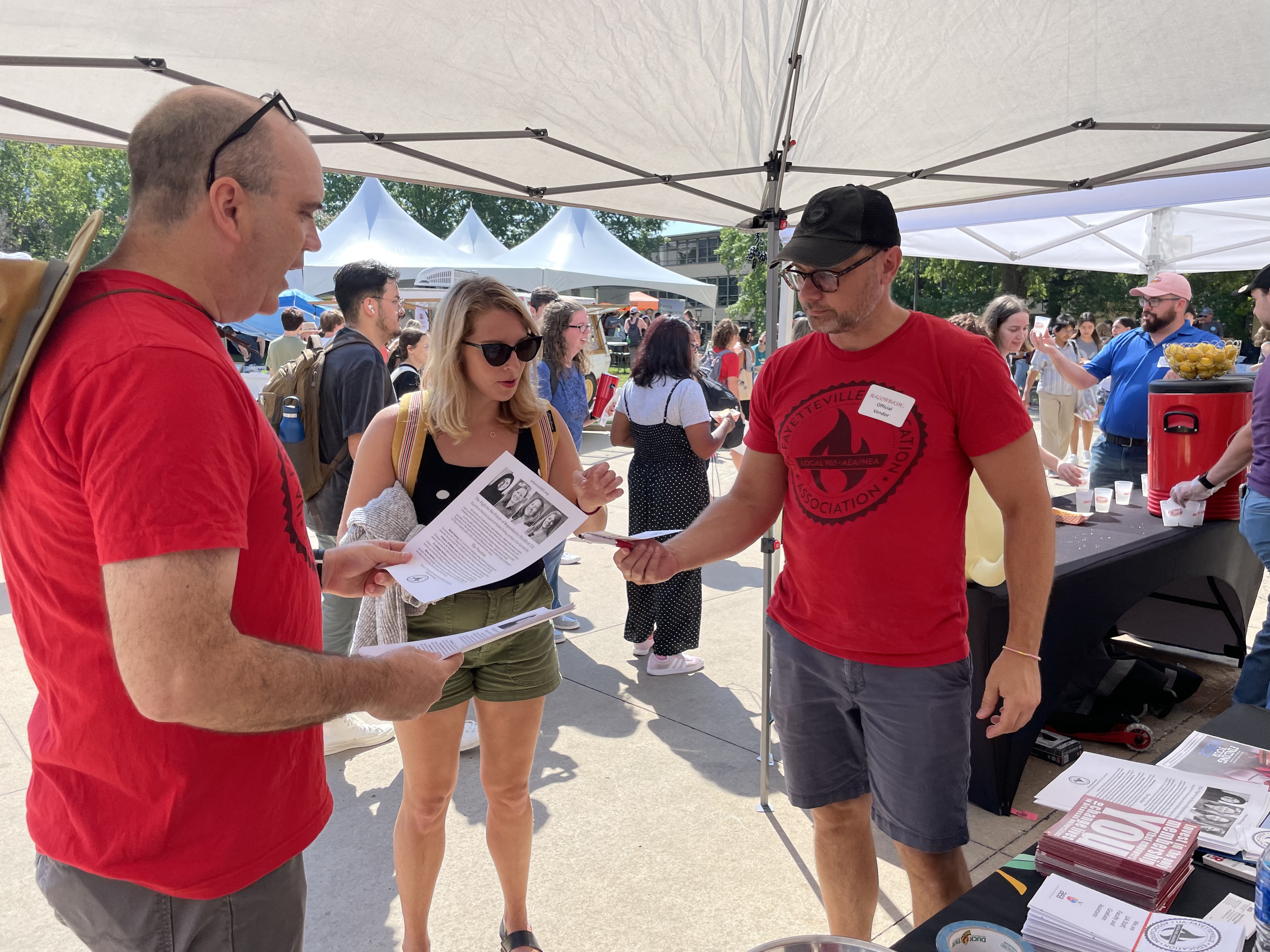 Local 965 Vice President Mike Pierce (left) and President Bret Schulte explain its plans and goals to a graduate teaching assistant Aug. 24 at the 2022 Razorbash community fair on the Fayetteville campus.