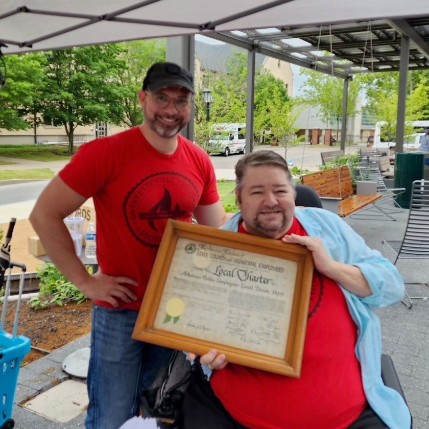 Local 965 President Hershel Hartford displays the 1966 charter of what first was the Arkansas Public Employees Local Union 965 after Past President Bret Schulte presented it to him at the 2023 University of Arkansas Staff Appreciation Picnic, May 17 at the 1021 Food Hall.