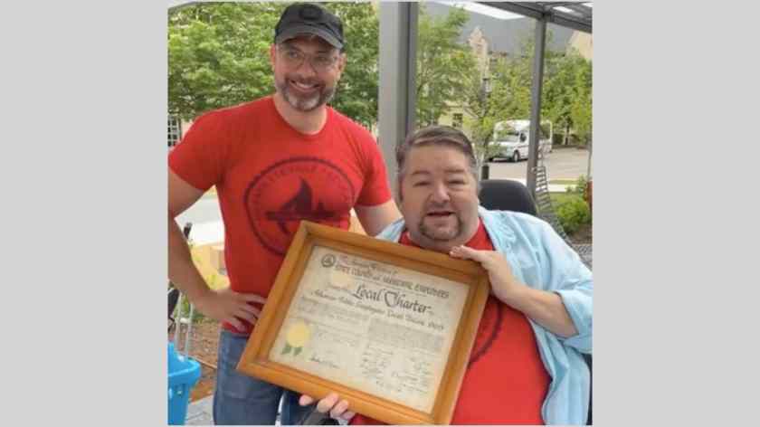 Local 965 President Hershel Hartford displays the 1966 charter of what originally was the Arkansas Public Employees Local Union 965 after Immediate Past President Bret Schulte presented it to him at the 2023 University of Arkansas Staff Appreciation Picnic, May 17 at the 1021 Food Hall.