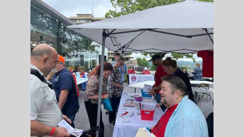 As University of Arkansas employees look at brochures, Local 965 President Hershel Hartford (light blue shirt) talks with a staff employee at the May 17, 2023, University of Arkansas Staff Appreciation Picnic at the 1021 Food Hall.