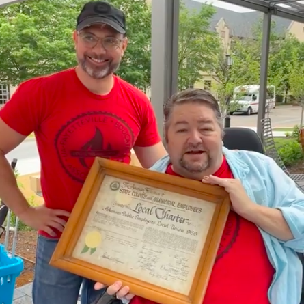 Local 965 President Hershel Hartford displays the 1966 charter of what originally was the Arkansas Public Employees Local Union 965 after Immediate Past President Bret Schulte presented it to him at the 2023 University of Arkansas Staff Appreciation Picnic, May 17 at the 1021 Food Hall.