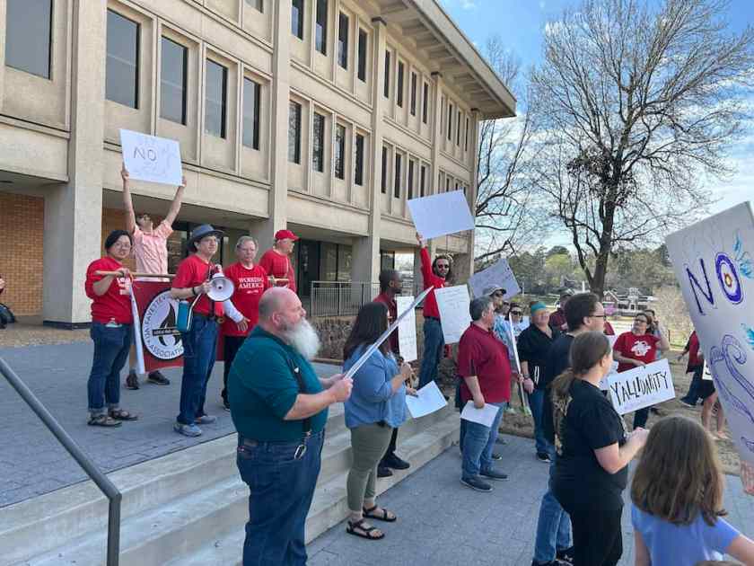 Over 2 dozen marchers face the other 2 dozen as all stop chanting "They say privatize: We say fight back!" at the Administration Building.