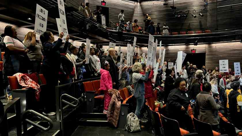 Many of the 200-plus people attending the indoor Freedom March Monday, Jan. 20, 2025, at Fayetteville's Theatre Squared briefly hoisted preprinted pickets to represent the 1968 Memphis sanitation workers strike that the late Martin Luther King Jr. visited.