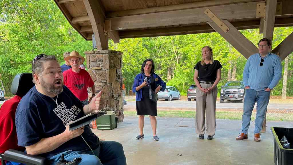 Local 965 President Hershel Hartford opens the 2025 May Day picnic as NWA Labor Council President Walter Hinojosa (from left), state Reps. Diana Gonzales Worthen and Denise Firmin Garner, and Blake Rutherford listen.