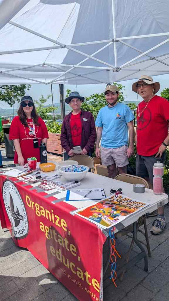 AEA Zone 1 UniServe rep Renee Johnson, Local 965 Vice President Ben Pollock and 965 board members James Kelly and Michael Pierce ready their booth May 14 at the 2025 Staff Appreciation Picnic of the University of Arkansas, Fayetteville.