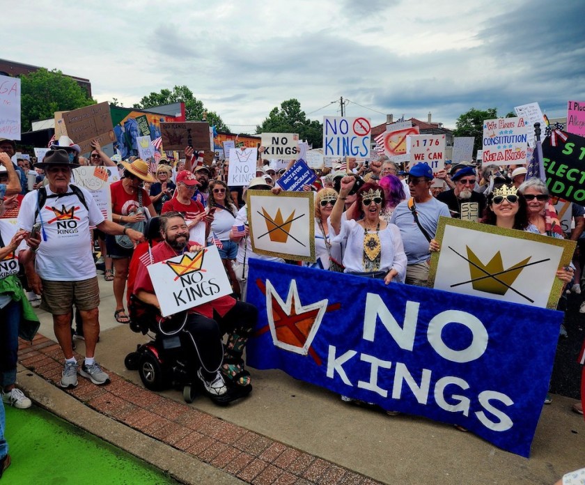 Hershel Hartford, president of UA-Fayetteville Education Association / Local 965, poses beside a banner at the Fayetteville, Arkansas, No Kings Day of Defiance rally Saturday, June 14, 2025. Photo by Denise Firmin Garner