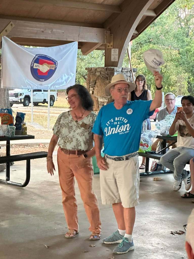 Walter Hinojosa, president of the Northwest Arkansas Central Labor Council (AFL-CIO), presents state Rep. Diana Gonzalez Worthen, D-Springdale, a cap signed by the late Texas Gov. Ann Richards.